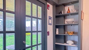 A room with a large window, a door, and a shelving unit with various items. - Coastal Antique farmhouse  (North Stonington)
