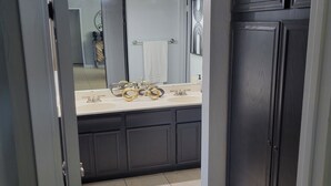 Ein Badezimmer mit dunklem Schrank, einem Waschbecken mit goldfarbenen Armaturen und einem Spiegel.