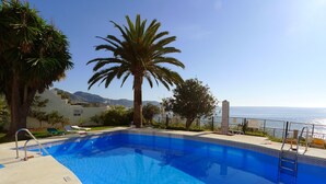 A clear blue swimming pool with a view of the ocean and mountains in the background. - R1353 | Tuhillo 8 1D by CG Nerja Rentals (Nerja)