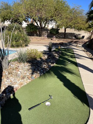 Un campo de práctica de golf con hoyo, rodeado de rocas y plantas.