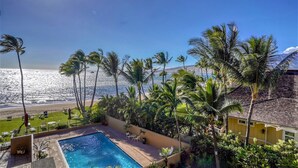 A pool area with a view of the ocean and palm trees. - Summer Special Pricing!  Oceanfront · Private Lanai · Heated Pool · Sunsets (Kihei)