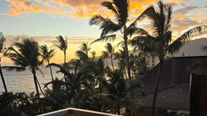 A sunset view with palm trees and a building in the foreground. - Summer Special Pricing!  Oceanfront · Private Lanai · Heated Pool · Sunsets (Kihei)