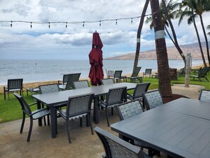 Ein Außenbereich mit Tischen und Stühlen mit Blick auf einen Strand und den Ozean.