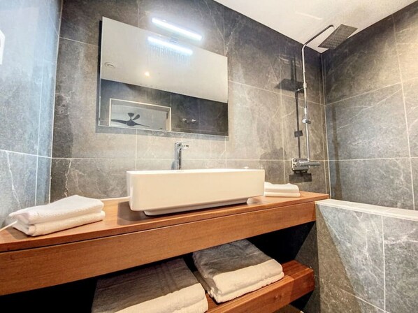 A modern bathroom with a large mirror, a white sink, and a shower.