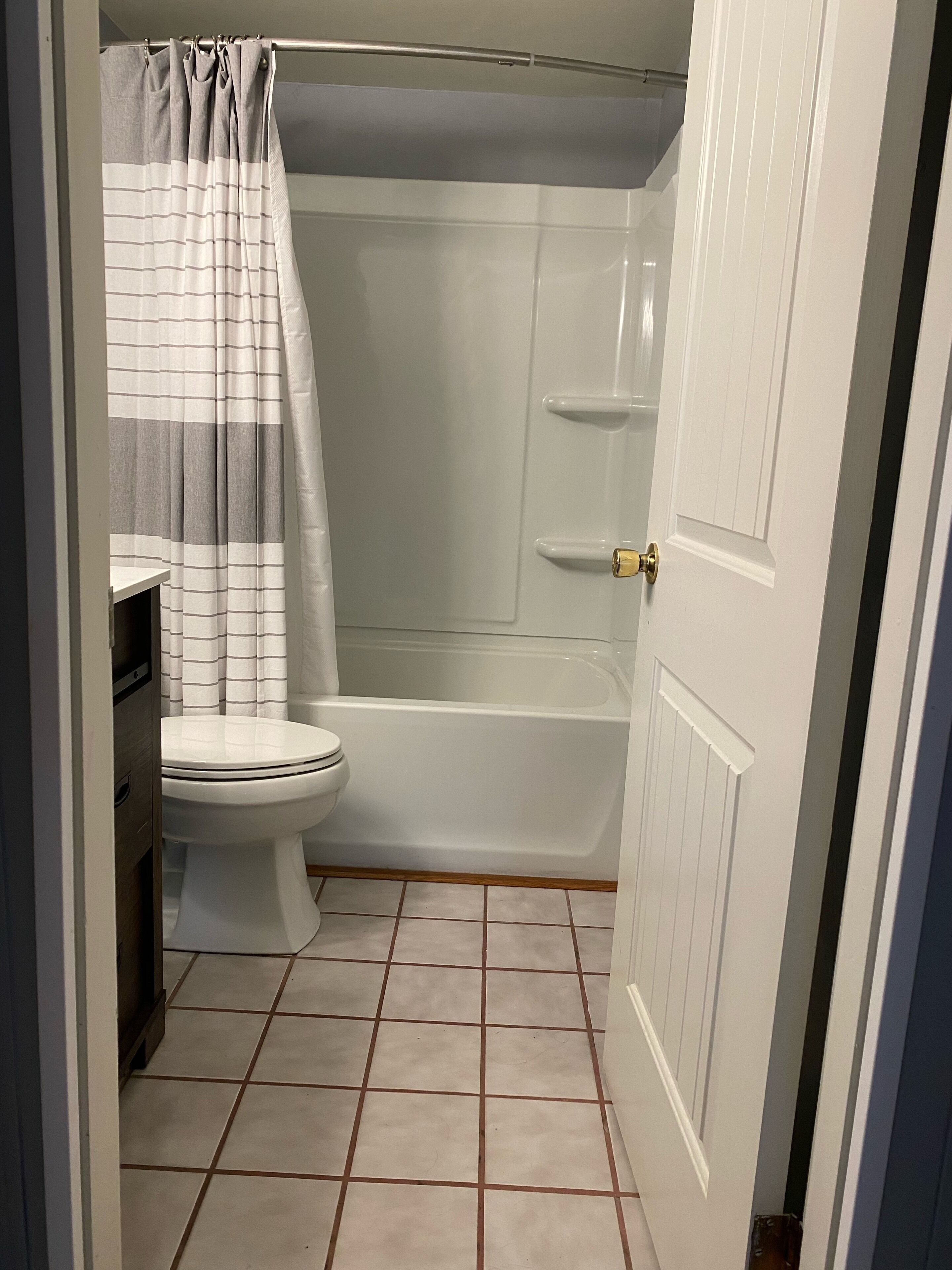 A bathroom with a toilet, a bathtub, and a shower curtain.