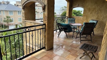 Ein Balkon mit Meerblick, ausgestattet mit einem Tisch, Stühlen und einem kleinen Holzschemel.