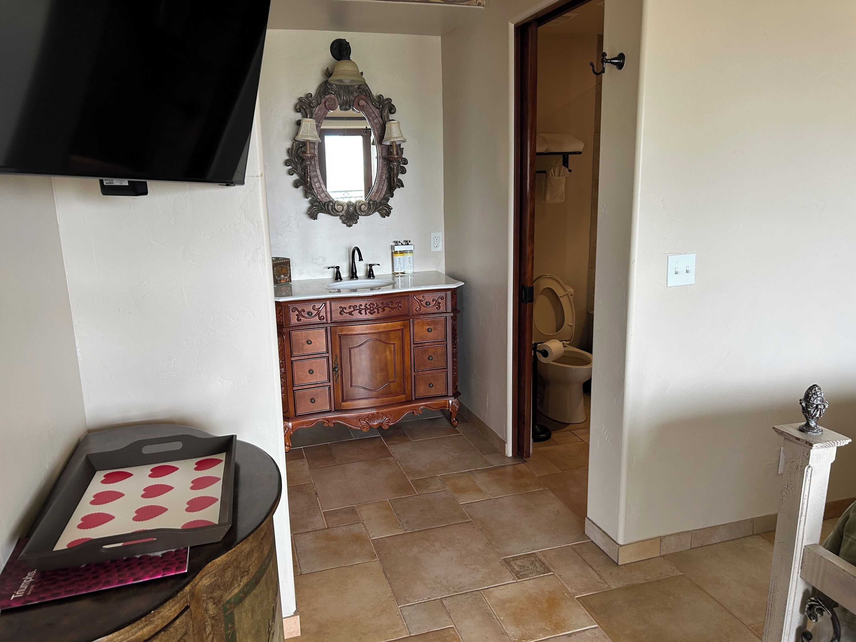 A bathroom with a wooden vanity, a mirror with two lights, and a toilet.