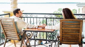 A couple seated at a table on a balcony with a view of the sea.