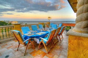Enjoy a meal with a view of the sea from this outdoor dining area, surrounded by a balustrade and a pillar.