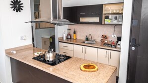 A modern kitchen with a gas stove, stainless steel range hood, and granite countertop.