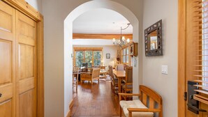 A hallway with wooden doors, a dining area with a table and chairs, and a bench.