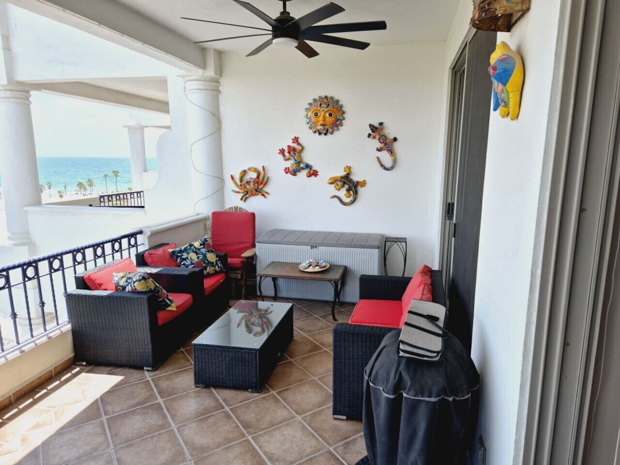 A balcony with wicker furniture, a ceiling fan, and decorative wall art.