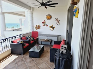 Ein Balkon mit Korbmöbeln, einem Deckenventilator und Wanddekoration.