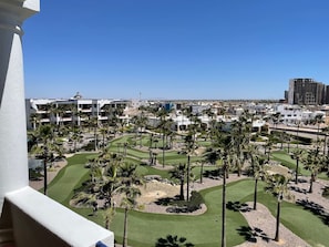 A golf course with palm trees and a view of a cityscape in the background.