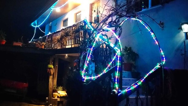 Une maison dotée d’un balcon et d’une grande structure décorative lumineuse à l’avant.