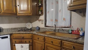 Une cuisine avec des meubles en bois, un plan de travail en granit, un évier en acier inoxydable et un égouttoir à vaisselle.