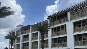 A hotel with a swimming pool, multiple balconies, and a clear sky. - The Pointe on 30A. Included 2 chairs with 1 umbrella beach set up + 2 bikes (Inlet Beach)