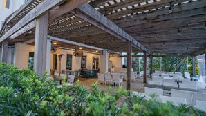 An outdoor patio area with wooden pergolas, tables, and chairs. - The Pointe on 30A. Included 2 chairs with 1 umbrella beach set up + 2 bikes (Inlet Beach)
