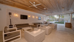 A spacious lounge area with multiple seating options, including sofas and chairs, a flat-screen TV mounted on the wall, and a ceiling fan. - The Pointe on 30A. Included 2 chairs with 1 umbrella beach set up + 2 bikes (Inlet Beach)