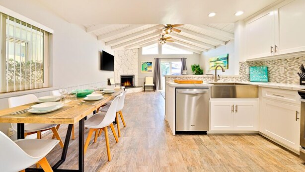 A modern kitchen with white cabinets, a wooden dining table, and a built-in oven. - Perfect 3 Bedroom Home between the Bay and Beach (Newport Beach)