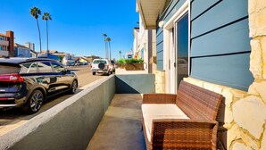 A balcony with wicker furniture, a stone wall, and a blue building facade. - Perfect 3 Bedroom Home between the Bay and Beach (Newport Beach)
