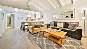 A spacious living room with a high ceiling, a dining area, and a kitchen in the background. - 6 Bedroom Home with Rooftop Deck Between the Bay & the Beach (Newport Beach)