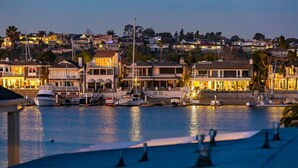 A marina with boats docked, waterfront buildings, and a view of the cityscape in the background. - 6 Bedroom Home with Rooftop Deck Between the Bay & the Beach (Newport Beach)