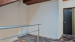 A staircase with a metal handrail, a black door with the number 106, and a marble floor. - Itsy Hotels Punest (Pune)