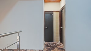 A hallway with a marble-tiled floor, a metal handrail, and a door marked with the number 106. - Itsy Hotels Punest (Pune)