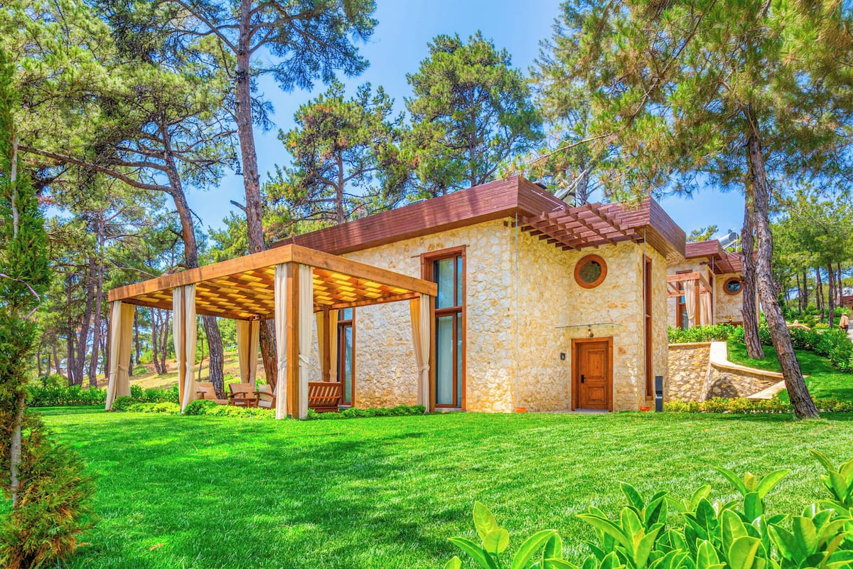 Ein Steinhaus mit einer Holzpergola und einer Tür.
