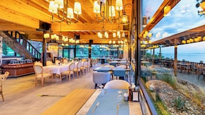 Un ristorante con un lungo tavolo, sedie e vista sull'acqua.