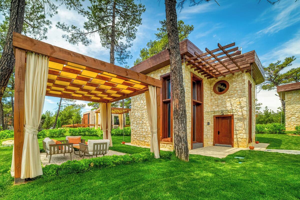 Ein Steinhaus mit einer Pergola, Sitzgelegenheiten im Freien und einem Kiesweg.