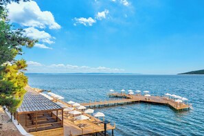 A wooden pier extending into a calm sea, with a covered seating area and umbrellas. - Marisstone Hotel Gökçetepe Tabiat Parkı (Kesan)
