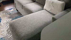 A living room with a grey sofa, a patterned rug, and a window with blinds. - Cozy Cottage 3 blocks to Town 7 to Beach 4 Blocks to Asbury (ocean grove)