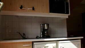 Ett kompakt kök med träskåp, en vit diskmaskin och en mikrovågsugn.