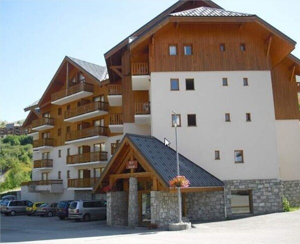 A multi-story hotel with a wooden facade, balconies, and a stone entrance.