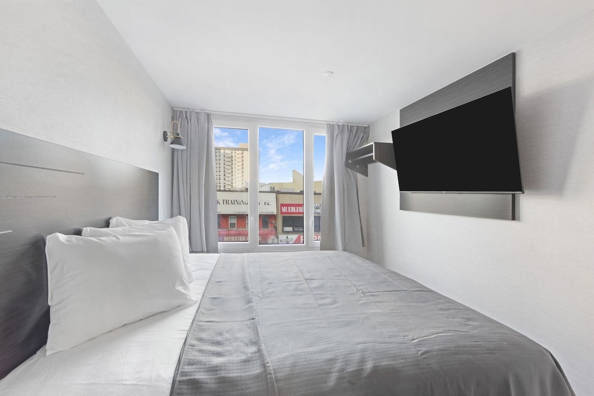 Habitación de hotel con una cama, un televisor de pantalla plana y vistas al exterior.