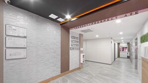 Un vestíbul d'hotel modern amb sòl de marbre, una recepció i diplomes emmarcades a la paret.