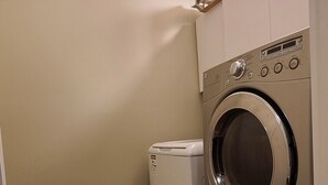 Un lavadero con lavadora y secadora, suelo de madera y pared de color claro.