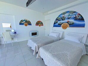 A hotel room with two beds, a desk with a chair, a TV, and decorative wall art.