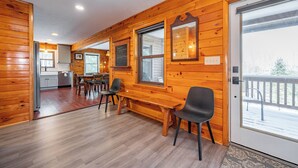 L’intérieur d’une cabane en bois comprend un coin repas, une cuisine et une grande fenêtre.