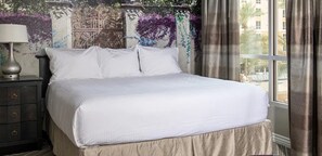 Un lit bien fait dans une chambre d’hôtel, avec vue sur l’extérieur par une fenêtre.