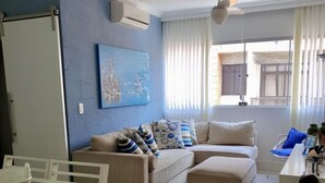 A living room with a sofa, ottoman, and a dining area with a table and chairs.