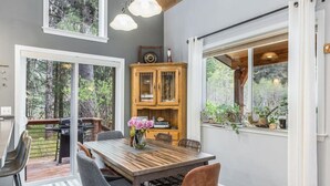A dining area with a wooden table, chairs, a cabinet, and a view of the outdoors. - Cottage in the Woods (Seward)