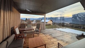 A covered outdoor deck with wooden furniture, a view of mountains, and a clear sky. - Eco-Chalet Matschiedl
Luxury mountainside Eco Chalet with stunning view -  (Kärnten)