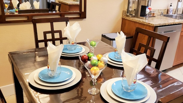 A dining table set with blue plates, napkins, and a centerpiece of colorful ornaments.