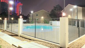 A fenced swimming pool area with a building in the background.