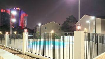 Ein eingezäuntes Schwimmbecken mit einem Gebäude im Hintergrund.