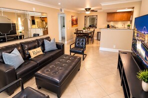 A modern living room with a leather sofa, ottoman, and a dining area with a chair and table.
