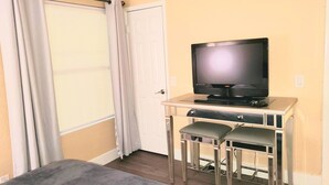 A room with a bed, a TV on a desk, a window with curtains, and a door. - 2BR Near Vegas Strip - 2 King Beds . Pool & Spa (Las Vegas)